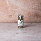 DELIGREECE Smoky Souvlaki Rub – Wildkräutermischung aus Kreta im Glas, fotografiert vor rustikalem Stein- und Holzuntergrund.