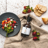 Erdbeer-Balsamico Flasche in Food-Styling Szene mit Erdbeeren und Brot
