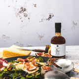 Feigen-Balsamico Flasche neben Salat mit Prosciutto, Feigen und Käse