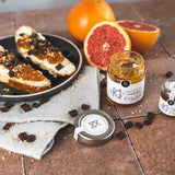 Grapefruit-Marmelade von DELIGREECE mit frischer Grapefruit und belegten Toastscheiben dekorativ angerichtet.