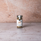 DELIGREECE Heavy Greek Steak Rub im Glas vor einer hellen Steinwand.