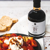 Honig-Balsamico Flasche neben Bruschetta mit Tomaten und Ricotta