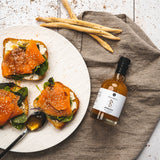 „Pfirsich-Balsamico Flasche neben Lachs-Toast mit Frischkäse und Sesam