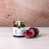 Pflaumen-Chutney von DeliGreece – fruchtiges Chutney im Glas, daneben eine aufgeschnittene Pflaume.