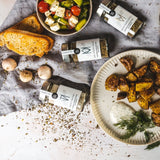 DELIGREECE Gewürze stilvoll arrangiert mit Ofenkartoffeln, Tzatziki, Feta-Salat, Toast und Knoblauch.