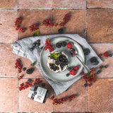 Frühstück mit Waldfrüchte Konfitüre auf Brötchen, dekoriert mit Beeren und frischer Minze