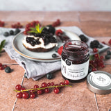 Offenes Glas Waldfrüchte Konfitüre mit Brot und Beeren dekoriert
